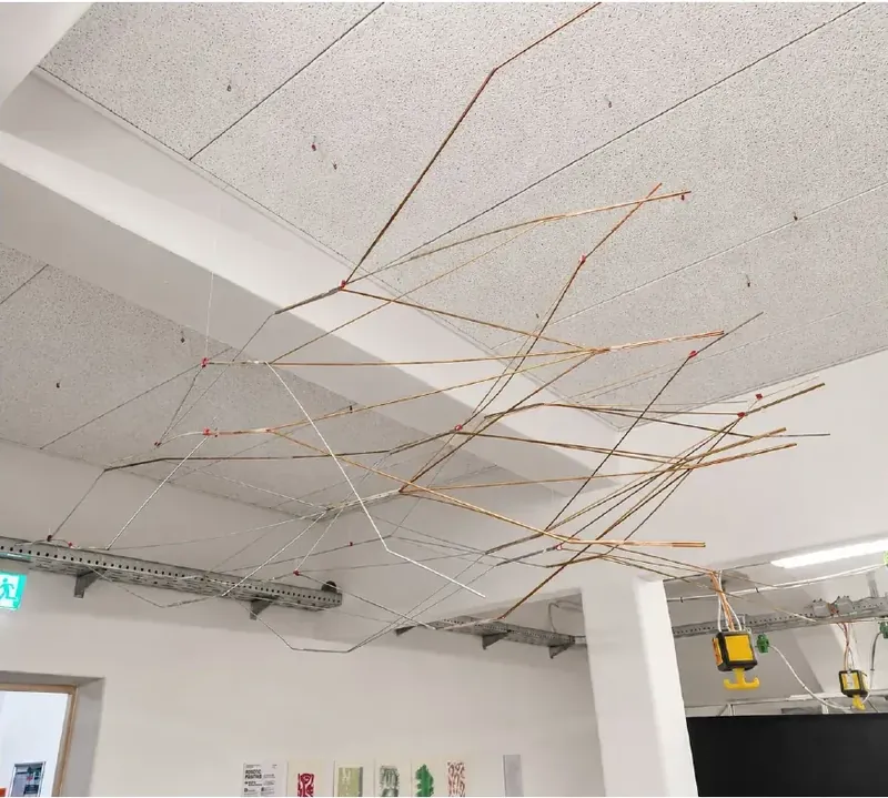 Suspended canopy of bent metal rods hanging under a studio ceiling