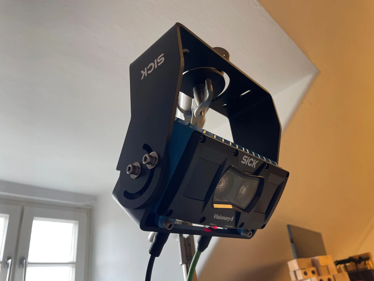 Close-up of the SICK Visionary-S sensor in its bracket, mounted above the workspace