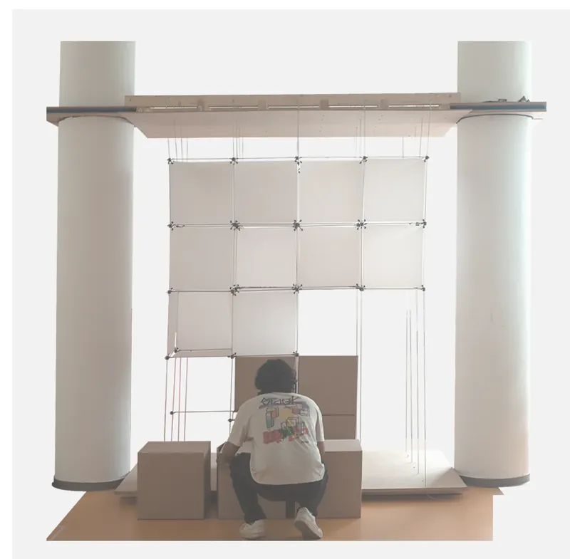 The physical voxel installation: a suspended grid of panels between two columns with a person seated inside